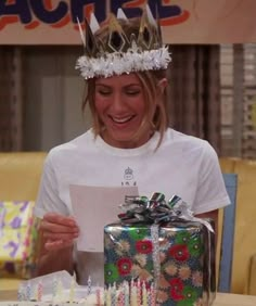 a woman wearing a crown holding a piece of paper in front of a birthday cake