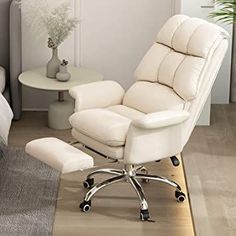 a white chair and footstool in a room with a bed on the other side