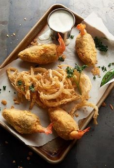 some fried food is on a tray with dipping sauces and garnishes