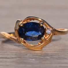 a close up of a ring with a blue stone in it on a wooden surface