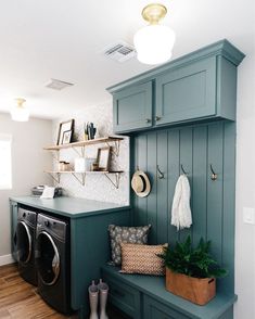 a washer and dryer in a laundry room with green cabinets, hanging hooks on the wall