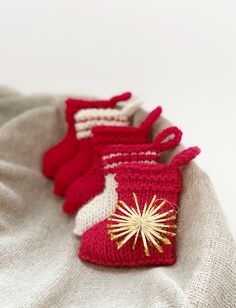 three knitted mittens sitting on top of a white blanket