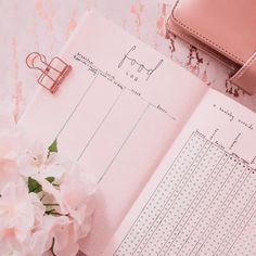 an open planner with pink flowers and a purse on the side, next to it