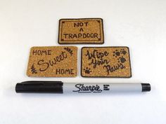 three coasters with words written on them and a marker next to them that says not a trapdoor