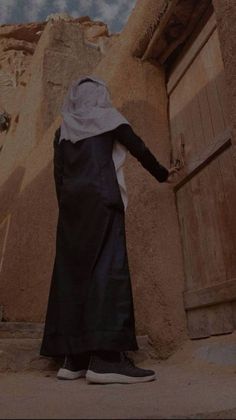 a person standing in front of a door with their hand out to the side, wearing a black and white outfit