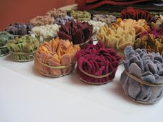 small baskets filled with different colored flowers on top of a white tablecloth covered table