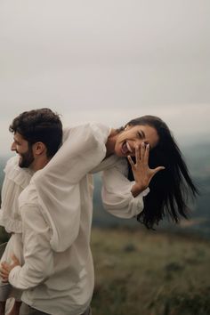 a man carrying a woman on his back while she holds her hand up to her face