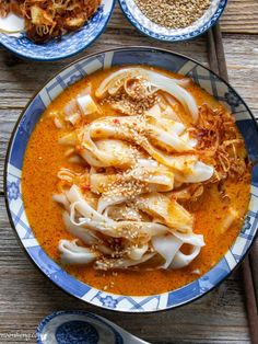 an overhead view of a bowl of soup with noodles and meats on the side