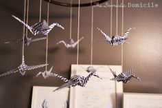 some origami birds are hanging from strings in the shape of cranes on a wall