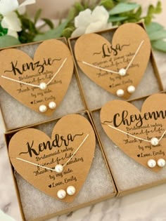 four heart shaped boxes with personalized necklaces in them on top of a table