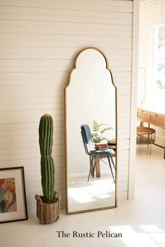 a large mirror sitting on the side of a wall next to a potted cactus