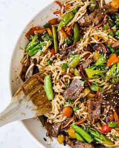 stir fried noodles with beef and vegetables in a white bowl