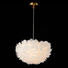 a chandelier with white feathers hanging from it's center point on a black background