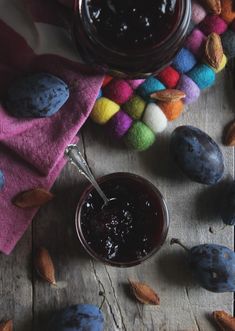 a bowl of fruit jam next to some nuts and a towel on a wooden table