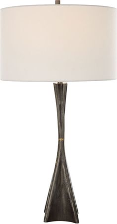 a table lamp with a white shade on the base and a black vase underneath it