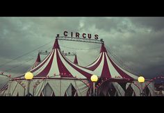 a circus tent with lights on it under a cloudy sky