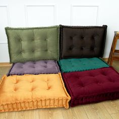 four different colored tufted cushions on the floor