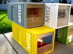 four containers are stacked on top of each other in front of a house with grass