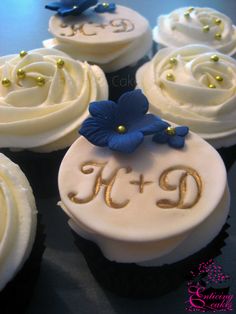 some cupcakes with white frosting and blue flowers on top are decorated with gold beads