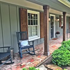 two rocking chairs on the front porch of a house with wood shutters and brick pavers