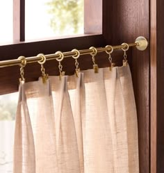 the curtains are hanging on the rod in front of the window with gold hardware and chain