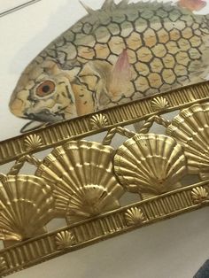 a gold fish is sitting on top of an ornate metal frame with scallops