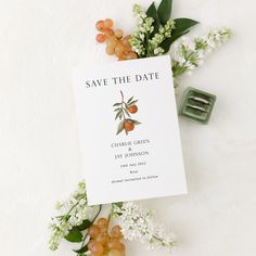 save the date card surrounded by flowers and berries on a white background with green clips