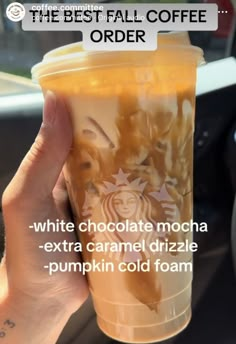 a person holding up a cup filled with liquid in their hand and the words, white chocolate mocha extra caramel drizzle pumpkin cold foam