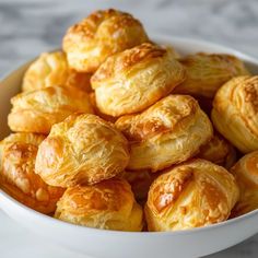 a white bowl filled with croissants sitting on top of a marble counter