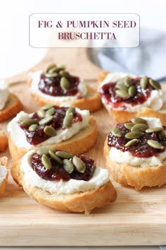 small sandwiches with cream cheese and pumpkin seeds on top are sitting on a cutting board