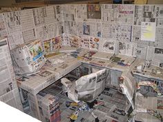 an office cubicle covered in newspapers and paper