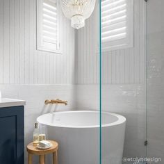 a white bath tub sitting next to a walk in shower under a chandelier