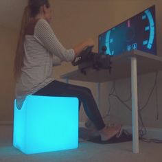 a woman sitting on top of a blue cube next to a computer monitor and keyboard