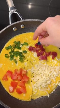 someone is cooking food in a pan with cheese and tomatoes on the side, along with other ingredients