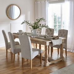 a dining room table with chairs and a vase filled with flowers on top of it