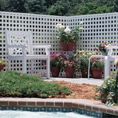 an outdoor pool with chairs and potted plants