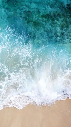 an aerial view of the ocean with waves crashing on it