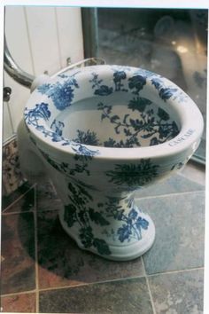 a blue and white toilet sitting on top of a tiled floor