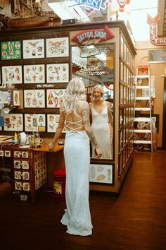 a woman standing in front of a store window with tattoos on it's back