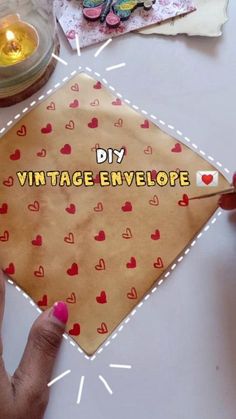 someone is holding a piece of paper with hearts on it and the words diy vintage envelope