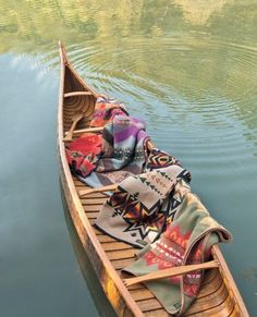 a canoe with blankets on it floating in the water