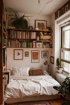 a bed sitting under a window next to a book shelf filled with lots of books