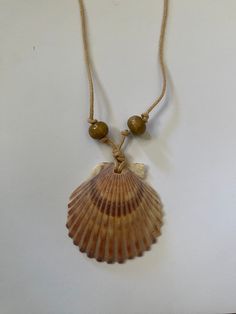 a necklace with a shell and beads hanging from it's side on a white surface