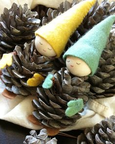 some pine cones and two little gnomes on top of one another with their faces covered in pine cones