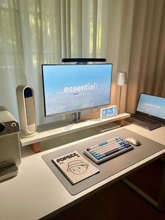 a computer desk with a laptop, keyboard and monitor on it next to a window