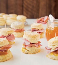 mini sandwiches with ham and cheese on them next to a jar of honey or syrup