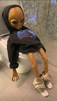 an alien sitting on top of a toilet in a bathroom