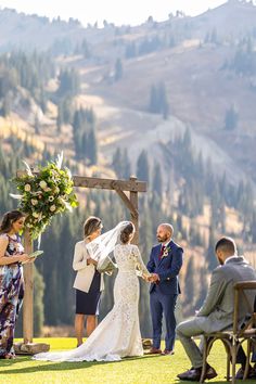 the bride and groom are getting married at their outdoor wedding ceremony in front of mountains