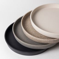 three plates stacked on top of each other with black rims and one white plate