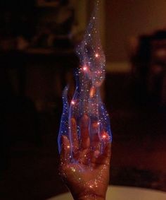 a person holding their hand up in the air with some lights on it's fingers